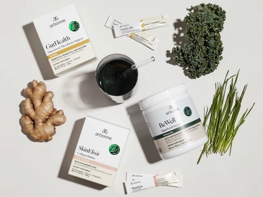 Arbonne Wellness Products Displayed With Natural Ingredients Like Kale And Ginger, Featuring BeWell Greens