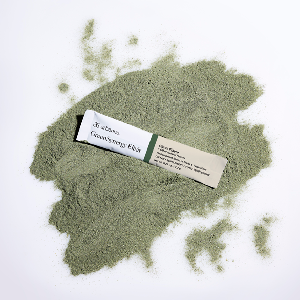 Arbonne GreenSynergy Elixir packet placed on a pile of green powder.
