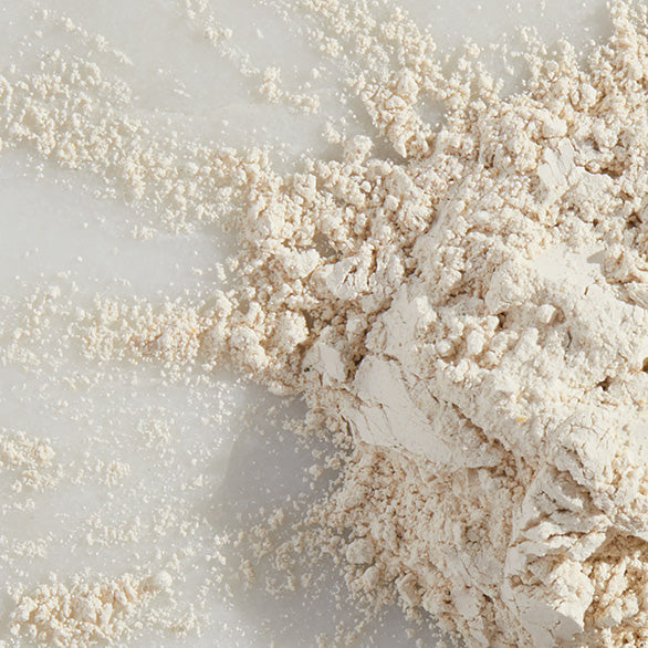 Close-up of Arbonne's natural gut health powder supplement, with a fine textured beige powder on a marble surface.